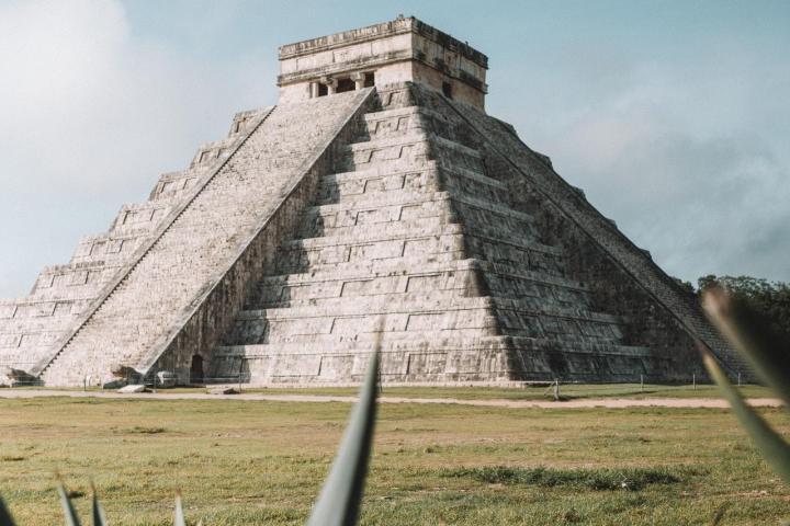 a close up of a fence with Chichen Itza in the background